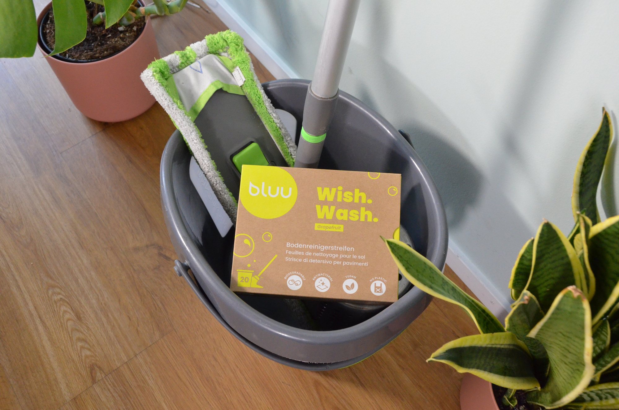 bluu – Wish.Wash-Verpackung auf einem Putzeimer mit Wischmopp (offizielles Produktfoto)