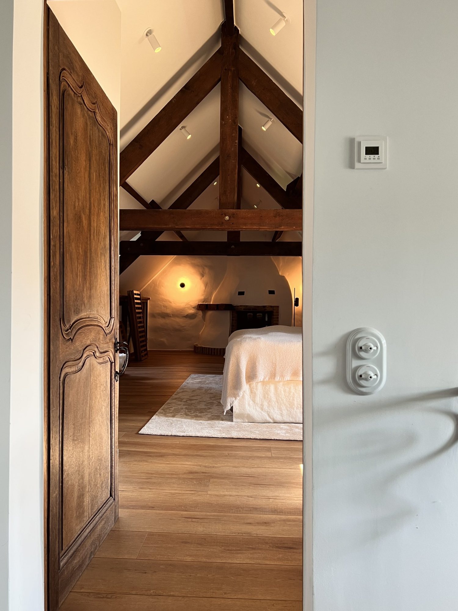 digitalSTROM – Blick durch eine Holztür in ein Dachgeschoss-Schlafzimmer mit Smart-Home-Taster (offizielles Kundenfoto)