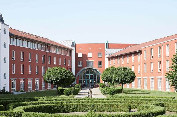 Gebäude einer MEDICLIN-Klinik: roter Backsteinbau mit Eingangsrotunde und angelegtem Gartenhof