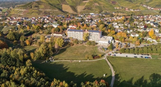 Luftaufnahme einer MEDICLIN-Klinik in Hanglage, umgeben von Wiesen, Weinbergen und Ortsbebauung